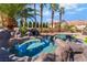 Backyard pool with an attached hot tub and a rock waterfall feature, surrounded by a lush landscaped backyard at 1407 Fields St, Las Vegas, NV 89142