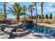 Backyard pool with an attached hot tub and a rock waterfall feature, surrounded by a lush landscaped backyard at 1407 Fields St, Las Vegas, NV 89142