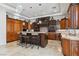 Well-equipped kitchen featuring wooden cabinets, granite island with stools, and tiled backsplash at 2 Yorkridge Ct, Henderson, NV 89052
