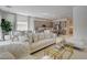 Bright living room featuring a tufted white sofa, gold accents, and an open floor plan to the kitchen and dining area at 21 Reverie Heights Ave, Henderson, NV 89011