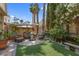Private backyard features mature landscaping, an artificial lawn, patio furniture, and a stone fountain at 2112 Preakness Pass, Las Vegas, NV 89117