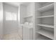 Functional laundry room features a washer, dryer, storage shelves, and neutral tile flooring at 2333 Silver Crew Pass, Henderson, NV 89052