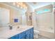 Bright bathroom featuring blue vanity with white countertop, bathtub and shower, with natural light from the window at 2496 Citrus Garden Cir, Henderson, NV 89052