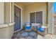 Cozy front porch features decorative metal art, and seating area with blue cushions and a stylish rug at 3434 Boleo Ct, Las Vegas, NV 89141