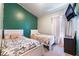 Shared bedroom featuring twin beds, white furniture, a green accent wall, and a mounted television at 3839 Dusty Glen Ct, North Las Vegas, NV 89032