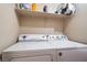 Laundry area featuring a full-size washer and dryer, along with upper shelving for storage at 3839 Dusty Glen Ct, North Las Vegas, NV 89032