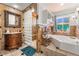 Elegant bathroom features a glass block shower, soaking tub, and custom vanity with marble countertop at 4406 Parkchester Cir, Las Vegas, NV 89108