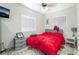 Bright bedroom featuring two windows, a ceiling fan, red comforter and a mounted television at 4406 Parkchester Cir, Las Vegas, NV 89108