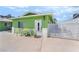 Charming green home with a white door and gated entry, showcasing a cozy outdoor seating area at 4406 Parkchester Cir, Las Vegas, NV 89108