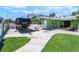 Green home showcasing a spacious driveway, artificial grass, and a covered patio area at 4406 Parkchester Cir, Las Vegas, NV 89108