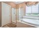 A primary bathroom features a glass shower stall, a soaking tub, and a chandelier at 4419 Via Bianca Ave, Las Vegas, NV 89141