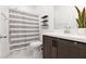 A bathroom featuring a shower with a striped curtain, modern shelves, and a sleek vanity with dark wood cabinets at 5136 Stonecrop St, North Las Vegas, NV 89031