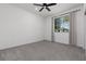 A bright bedroom featuring a ceiling fan, neutral carpet, and natural light streaming through a window at 5136 Stonecrop St, North Las Vegas, NV 89031