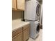 Efficient laundry area with a stacked washer and dryer unit and adjacent cabinet with tiled countertop space at 5201 S Torrey Pines Dr # 1253, Las Vegas, NV 89118