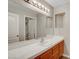 Bathroom features a large mirror with decorative lighting and a white tile countertop with wood cabinets at 5373 Painted Mirage Rd, Las Vegas, NV 89149