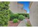 Exterior side view featuring a landscaped walkway, lush green bushes, and neutral exterior paint at 5373 Painted Mirage Rd, Las Vegas, NV 89149