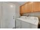 Laundry room features side-by-side white washer and dryer with upper wood cabinets at 5373 Painted Mirage Rd, Las Vegas, NV 89149