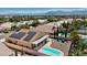 Aerial view showcases a home with a solar-paneled roof, desert landscaping, and a backyard pool and covered patio at 5812 Spinnaker Reach Ave, Las Vegas, NV 89130