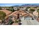 Aerial view features a single-Gathering home with a three-car garage, desert landscaping, and a tile roof at 5812 Spinnaker Reach Ave, Las Vegas, NV 89130