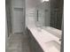 Bright bathroom featuring double sinks, gray cabinets, and a glass-enclosed shower at 6450 Spring Jog St, Las Vegas, NV 89166
