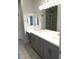 Modern bathroom with double sinks, gray cabinets, and a tiled shower at 6450 Spring Jog St, Las Vegas, NV 89166