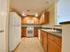 Bright kitchen featuring wood cabinetry, white appliances, and a convenient breakfast bar at 6635 Flaminian Ln # 104, North Las Vegas, NV 89084