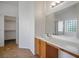 Bathroom featuring sink with wood cabinets, large mirror, and walk in closet at 7755 Pacific Rim Ct, Las Vegas, NV 89139