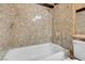 Bright bathroom featuring bathtub, shower and textured stone tiling at 8024 Hackberry Dr, Las Vegas, NV 89123