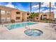Exterior view of community pool and hot tub featuring lounge chairs, palm trees, and apartment buildings at 8101 W Flamingo Rd # 1035, Las Vegas, NV 89147