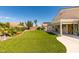 Grassy backyard featuring mature trees, an extended covered patio, and desert landscaping at 8204 Turbys Treehouse Pl, Las Vegas, NV 89131