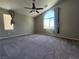 Spacious bedroom featuring plush carpeting, a ceiling fan, and a large arched window with natural light at 10400 Beachwalk Pl, Las Vegas, NV 89144