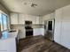 Modern kitchen with stainless steel appliances, white cabinetry, and stylish dark wood flooring at 10400 Beachwalk Pl, Las Vegas, NV 89144