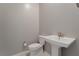 Modern powder room with a pedestal sink and toilet against a neutral wall at 10793 Pastel Sunset Ct, Las Vegas, NV 89135