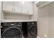 Bright laundry room has modern washer and dryer with white cabinets at 10793 Pastel Sunset Ct, Las Vegas, NV 89135
