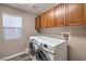 Laundry room with a front load washer and dryer and wooden cabinets at 11219 Playa Bonita Ave, Las Vegas, NV 89138