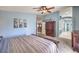 A view of the main bedroom with light blue walls, carpet flooring, ceiling fan, and access to the main bath at 11219 Playa Bonita Ave, Las Vegas, NV 89138
