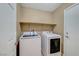 Bright laundry room features modern white washer and dryer, overhead shelving, and a neutral color scheme at 11420 Ogden Mills Dr # 101, Las Vegas, NV 89135
