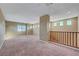 Open loft with carpet flooring, windows, and a staircase with wooden railings at 11420 Ogden Mills Dr # 101, Las Vegas, NV 89135