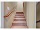 Carpeted staircase featuring neutral colored walls and wooden handrail at 11420 Ogden Mills Dr # 101, Las Vegas, NV 89135