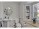 Bright bathroom featuring a pedestal sink, round mirror, and natural light from the window with plantation shutters at 1700 Red Rock St, Las Vegas, NV 89146