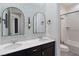 Well-lit bathroom with dual vanity, decorative mirrors, and shower with shower curtain at 3218 Mura Del Prato Ave, Henderson, NV 89044