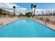 Community pool with crystal-clear water, surrounded by palm trees and a secure fence for a relaxing atmosphere at 3642 Haverhill St, Las Vegas, NV 89121
