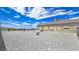 View of the gravel backyard and the rear of the house and propane tank behind a fence at 3780 Shawnee Ave, Pahrump, NV 89048