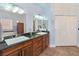 Bright bathroom featuring double sinks, wood cabinets, a large mirror, and a closet at 3780 Shawnee Ave, Pahrump, NV 89048