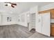 Bright living room with wood floors, white walls, ceiling fan, and kitchen with pantry and stainless steel refrigerator at 4439 Yellow Harbor St, Las Vegas, NV 89129