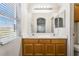 Well-lit bathroom featuring double sinks, a large mirror, warm-toned cabinetry and window with natural light at 4608 Snake Eyes St # 102, Las Vegas, NV 89122