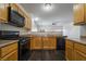 Well-lit kitchen featuring wooden cabinets, black appliances, and an open design with dark, modern flooring at 4608 Snake Eyes St # 102, Las Vegas, NV 89122