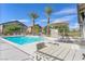 Community pool featuring lounge chairs, palm trees, table with umbrella, and a clear blue sky, promising relaxation at 4650 Ridgeley Ave # 103, North Las Vegas, NV 89084