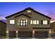 Stunning exterior of a three-story home showcases a three-car garage and classic desert architecture at twilight at 4650 Ridgeley Ave # 103, North Las Vegas, NV 89084