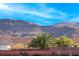 Scenic backyard featuring a brick wall, lush palm trees, and picturesque mountain views under a clear blue sky at 52 Vallejo Verde St, Henderson, NV 89012